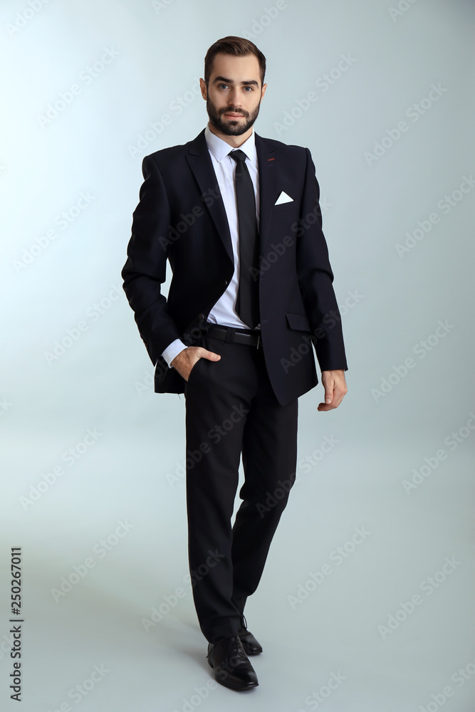 Handsome fashionable man in formal clothes against light background