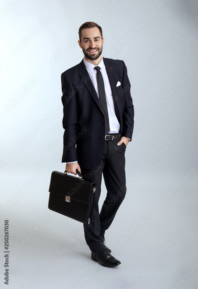 Handsome fashionable businessman against light background