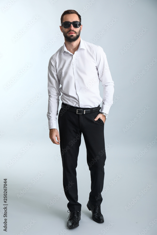 Handsome fashionable man in formal clothes against light background