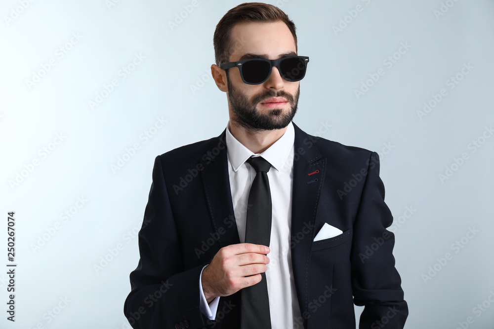 Handsome fashionable businessman against light background