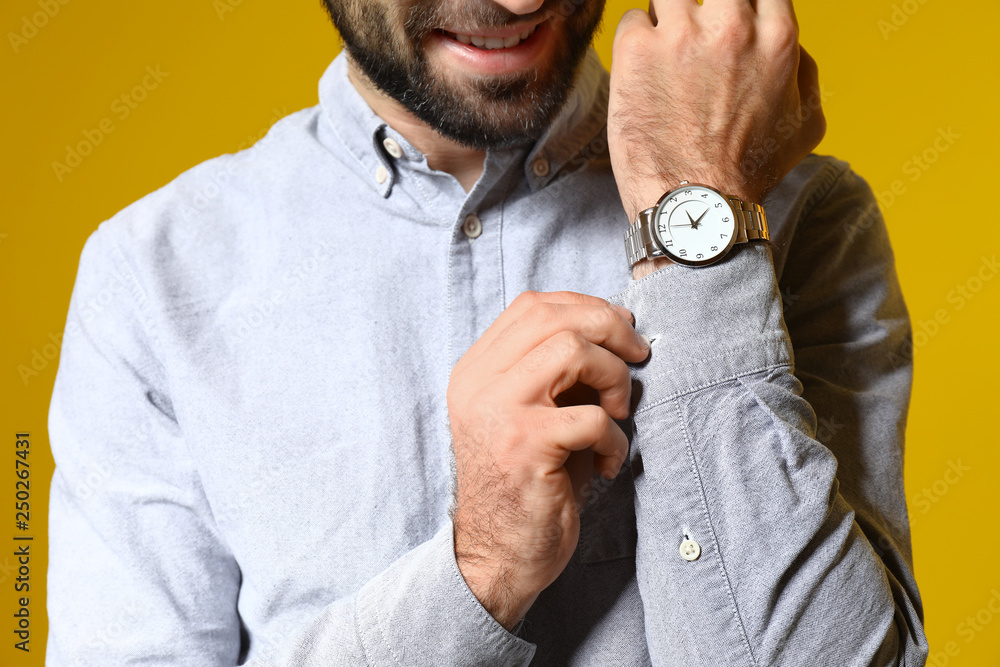 Handsome fashionable man with watch on color background, closeup