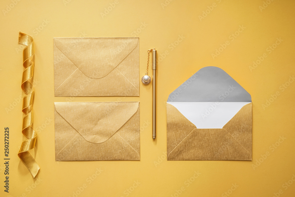 Paper envelopes, ribbon and pen on color background