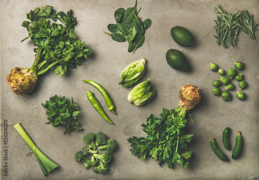 Healthy vegan salad ingredients layout. Flat-lay of green vegetables and herbs over grey concrete ta