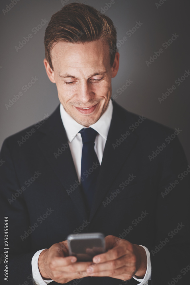 Young business executive sending text messages against a gray ba