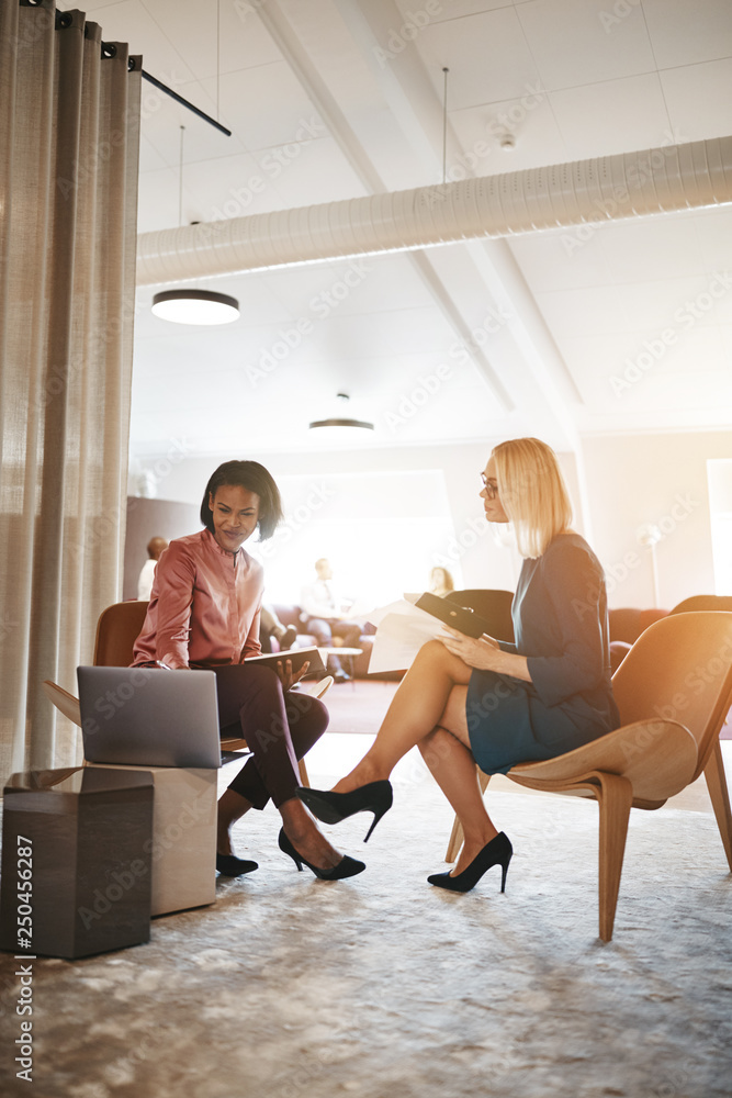 Two smiling businesswomen talking together in an office