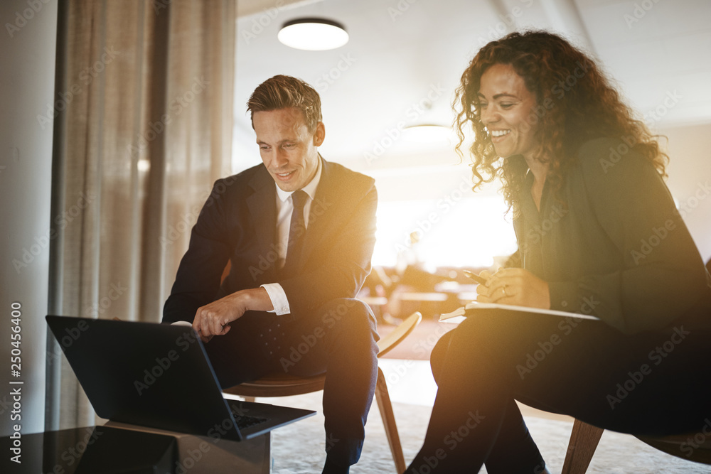 Two diverse businesspeople discussing work together on a laptop