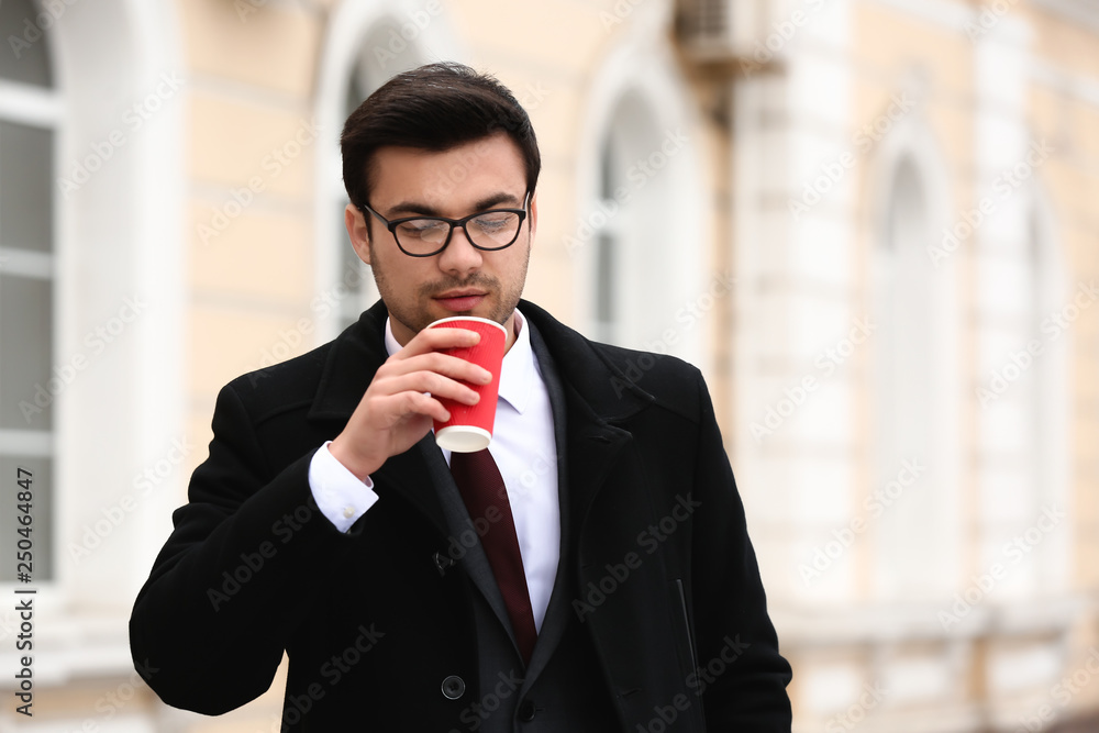 Handsome young businessman drinking coffee outdoors