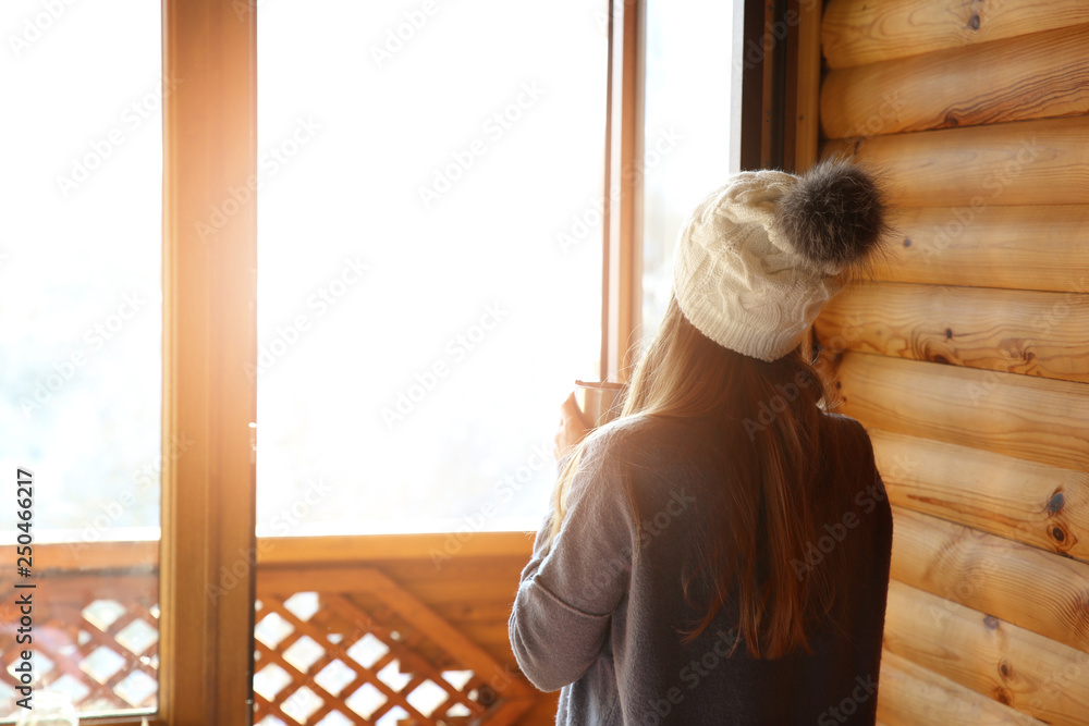 Woman drinking hot mulled wine near window in morning