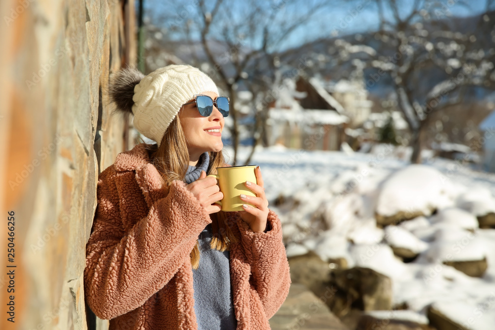 Woman with cup of hot mulled wine resting at resort