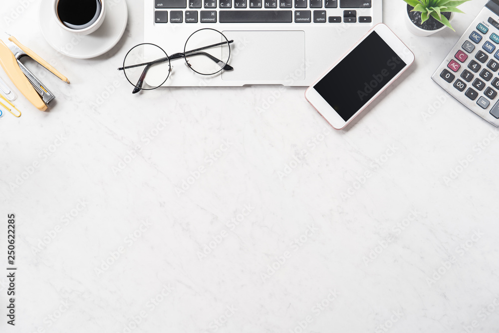 Stylized clean marble office working desk with smartphone, laptop, glasses and coffee cup, workspace