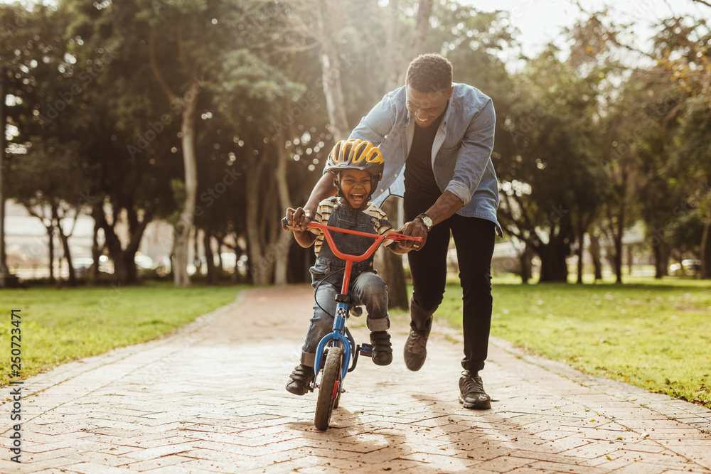 Father teaching his son cycling at park