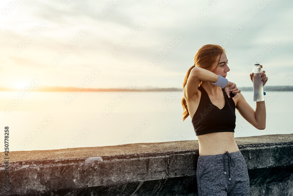 亚洲女性在早上锻炼和跑步，她在热身并喝淡水