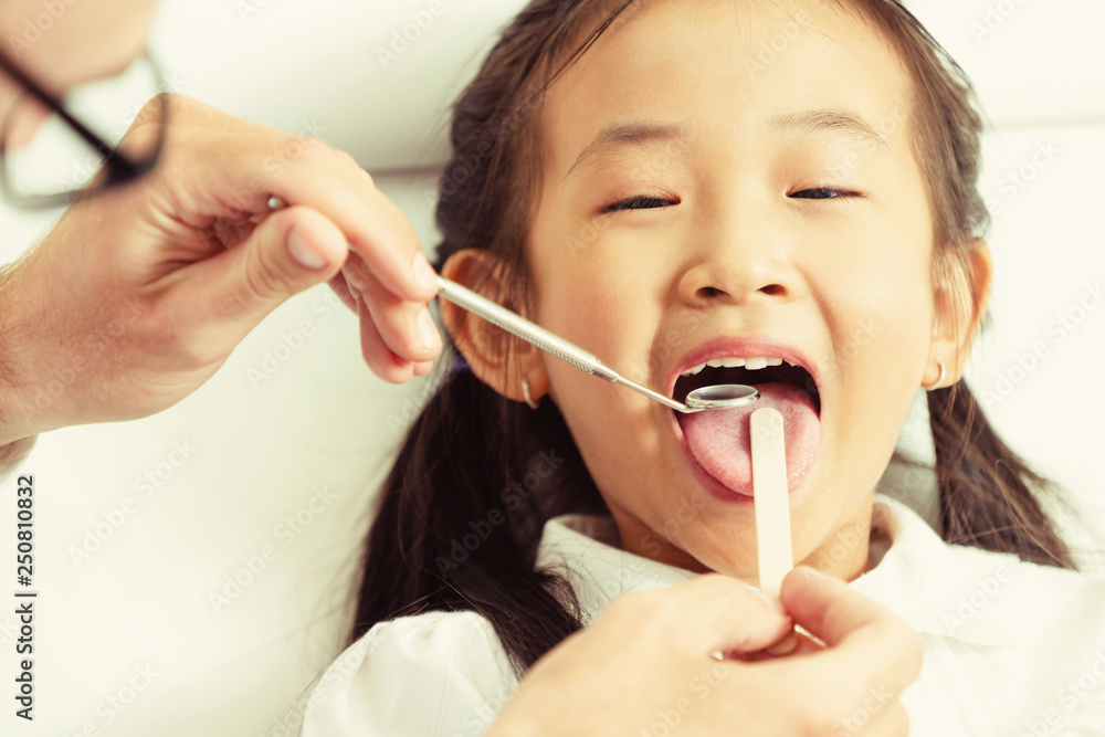 Dentist examining child teeth in dental clinic.