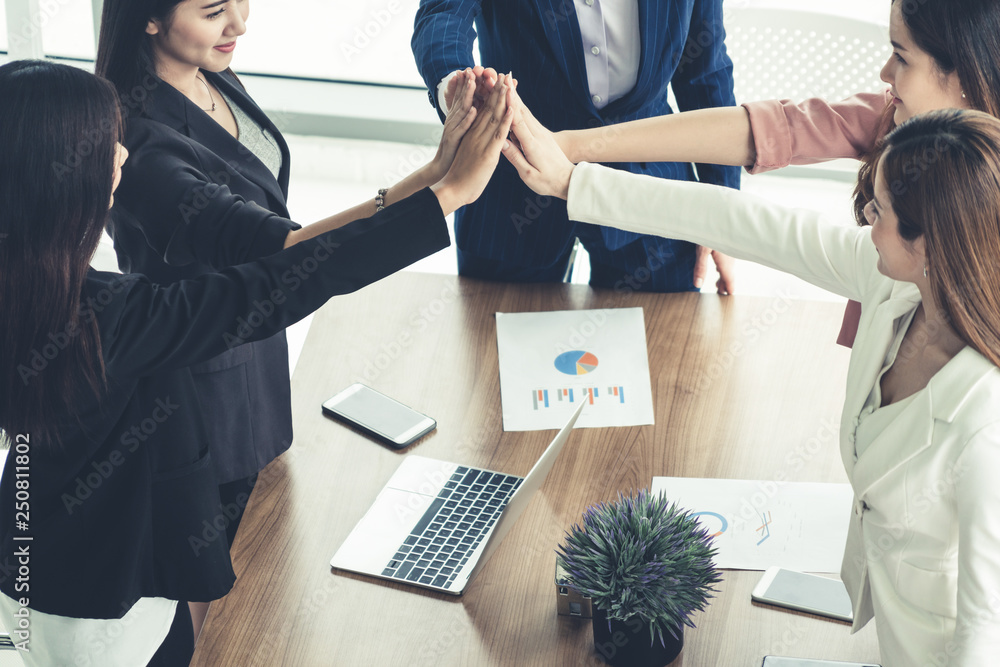 Teamwork businesswomen joining hands in meeting.