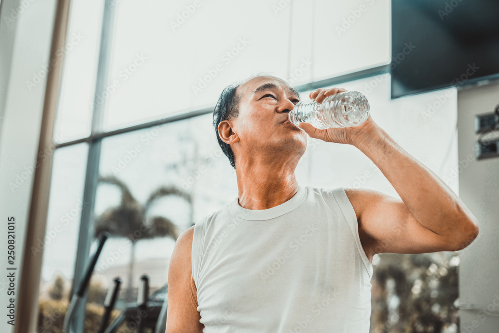 Senior man drink mineral water in fitness center.