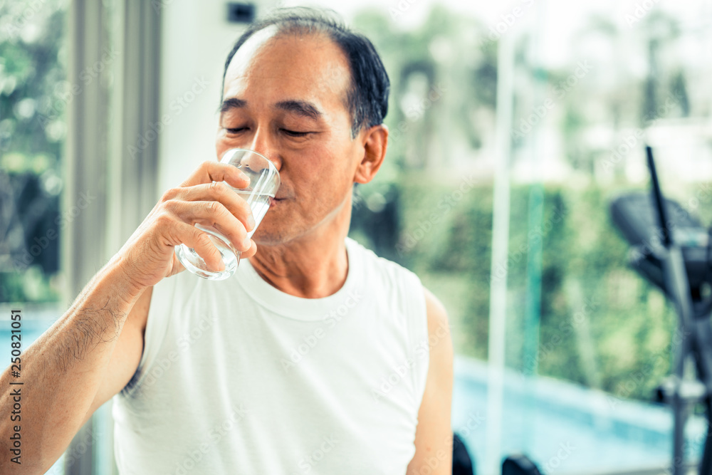 Senior man drink mineral water in fitness center.