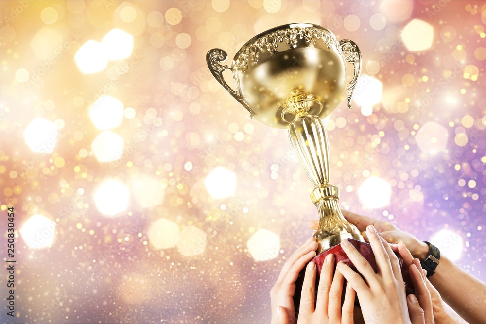 Hands holding golden trophy on light background