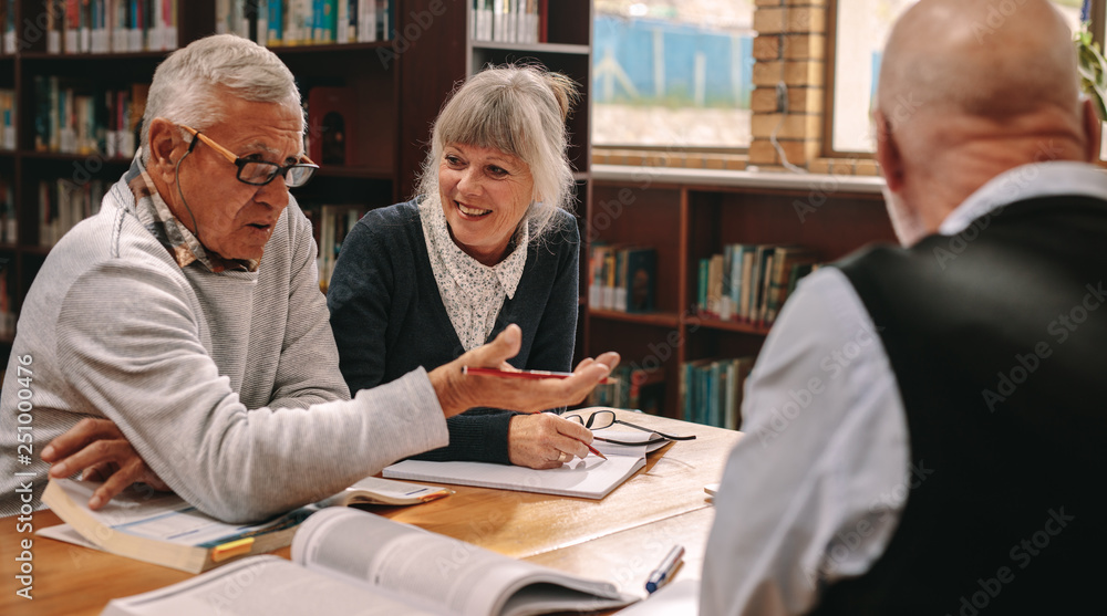 Senior classmates having a discussion sitting in a library