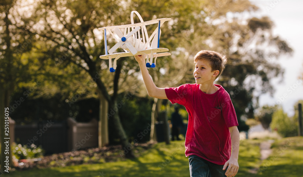 Boy playing with a toy plane in the park