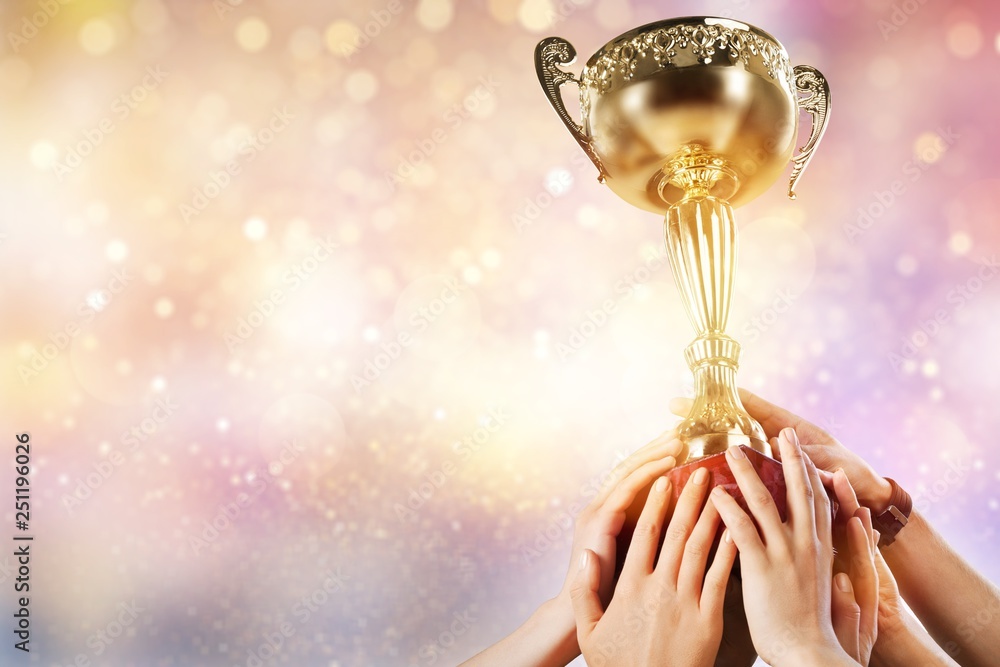 Hands holding golden trophy on light background