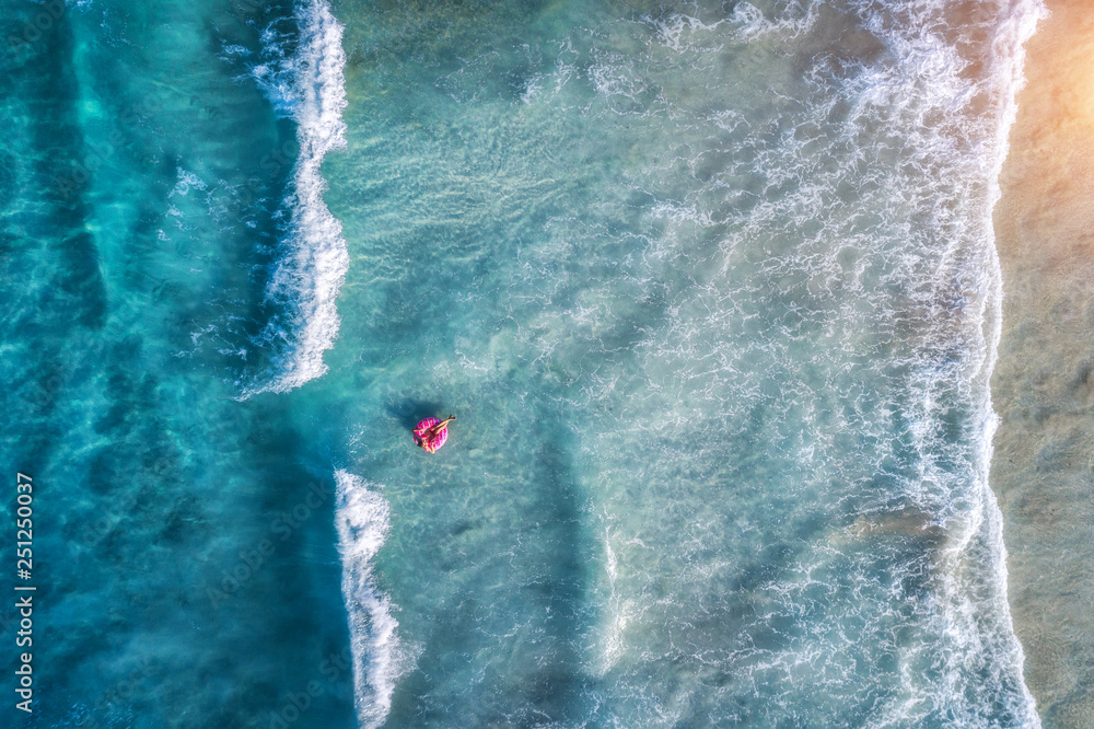 Aerial view of a young woman swimming with the donut swim ring in the пїЅlear blue sea with beautifu