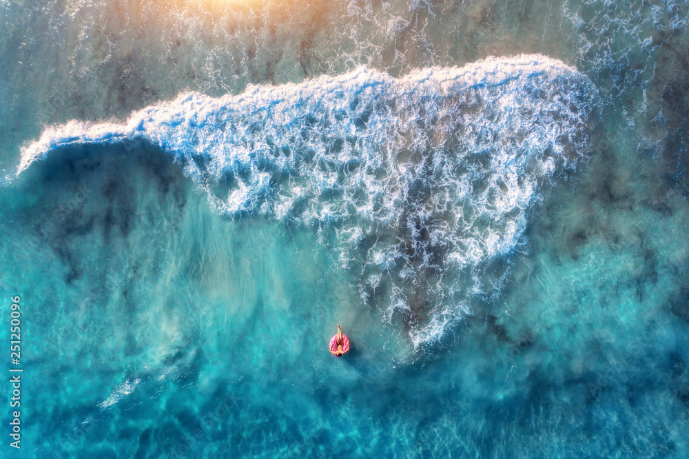 Aerial view of a young woman swimming with the donut swim ring in the пїЅlear blue sea with beautifu