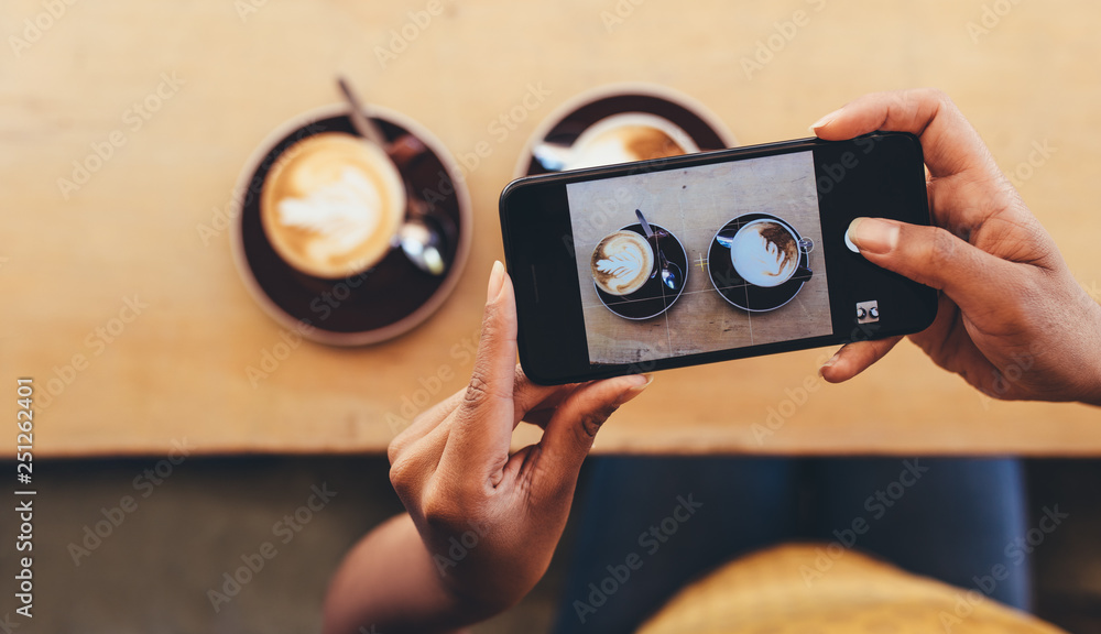 Woman photographing coffee with smart phone