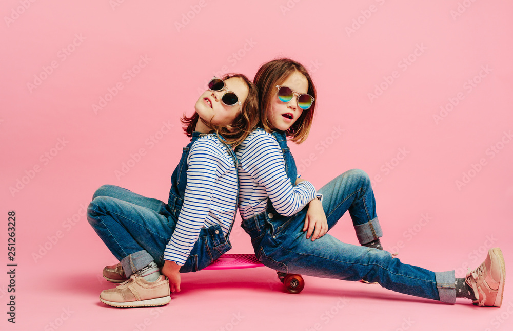 Stylish cute girls in fashion clothes on a skateboard