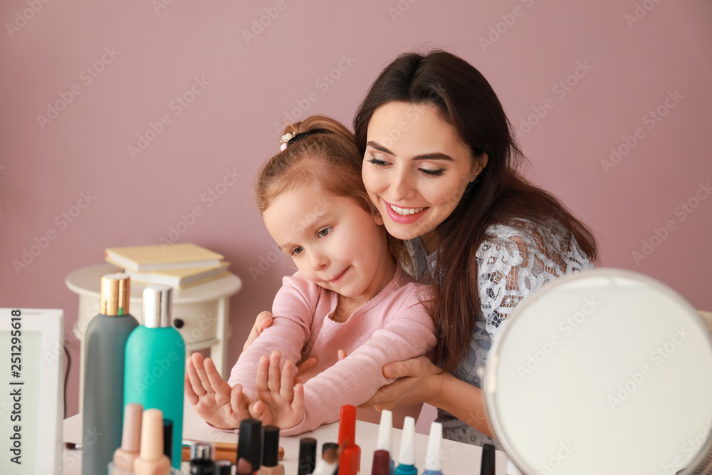 Cute daughter with mother making manicure at home