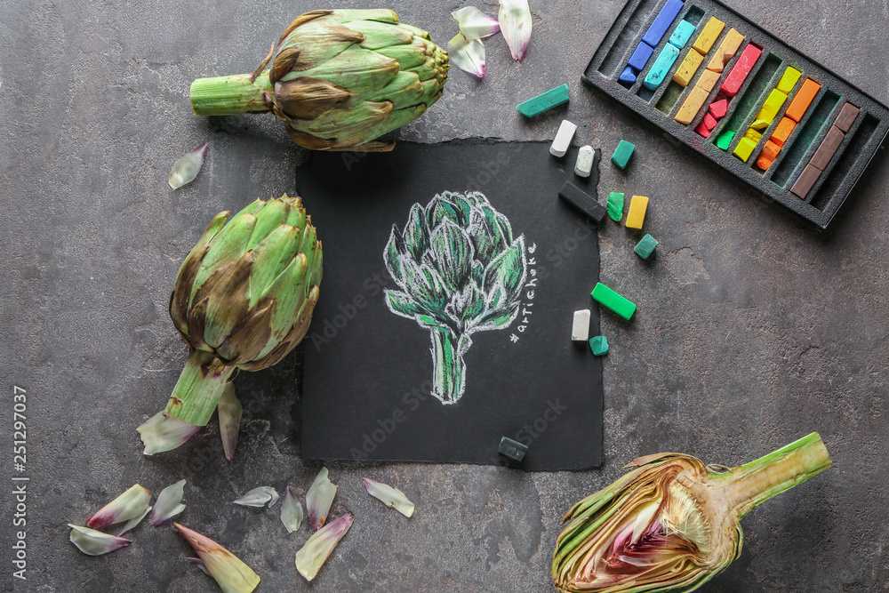 Tasty raw artichokes with picture on grey table