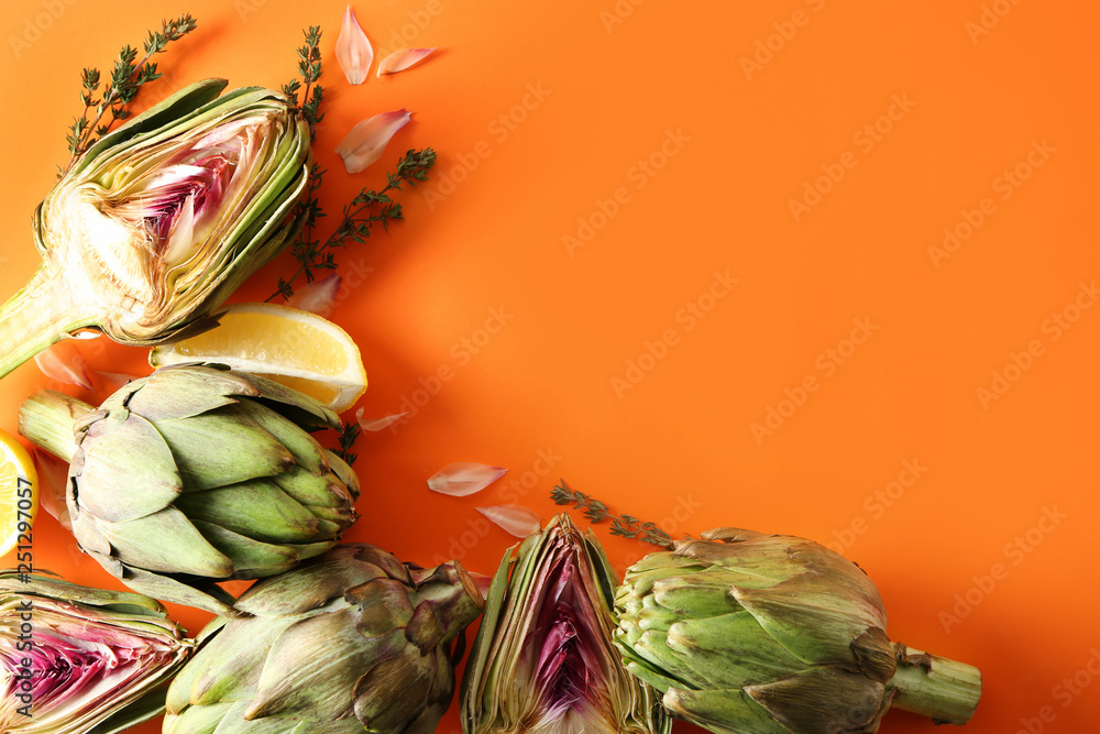 Tasty raw artichokes with lemon on color background