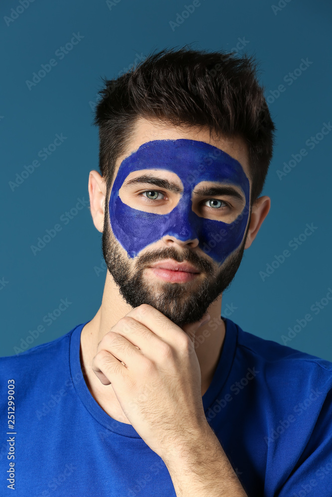 Portrait of handsome man with paint on his face against color background