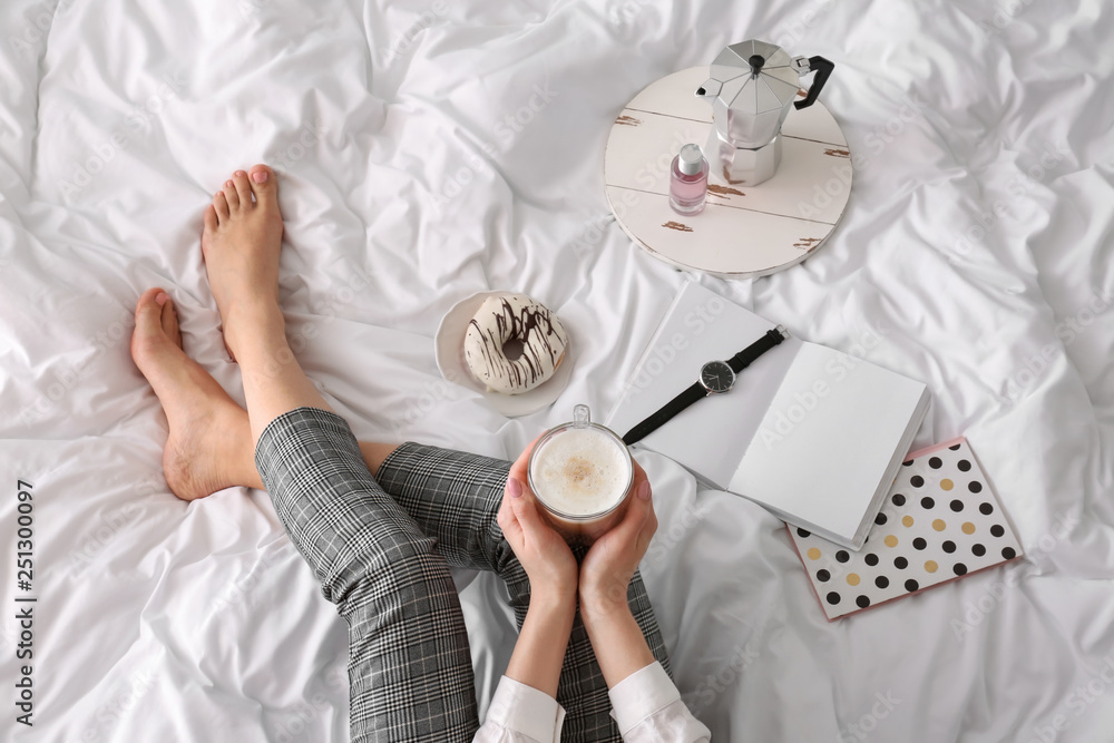 Young woman drinking coffee on bed in morning