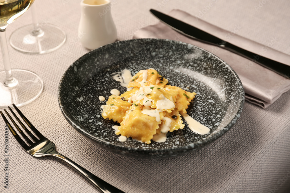 Plate with tasty ravioli on table