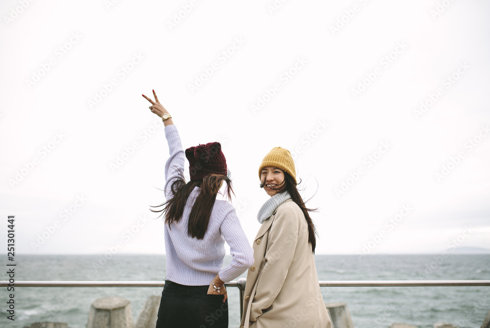 Two women standing together near the sea