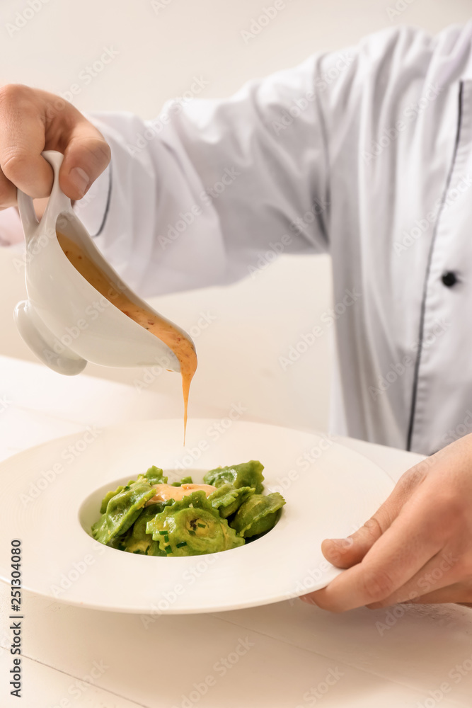 Male chef preparing for serving tasty ravioli on table