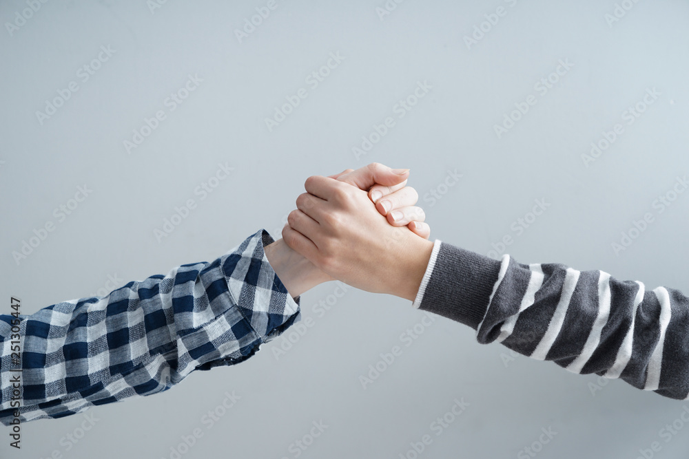 Women holding hands together on grey background. Friendship concept