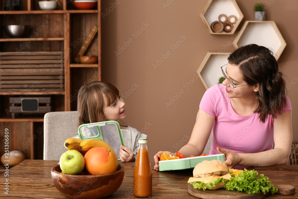 妈妈带着可爱的女儿在家准备学校午餐