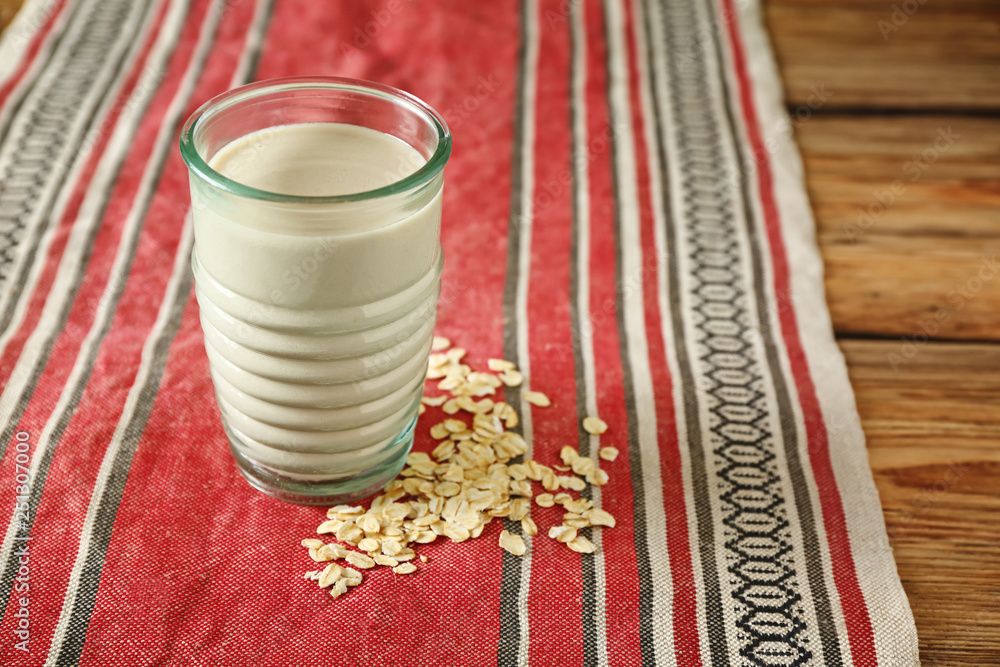 Glass of tasty oat milk on table