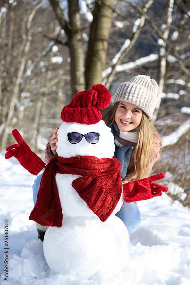 Happy woman with funny snowman on winter day