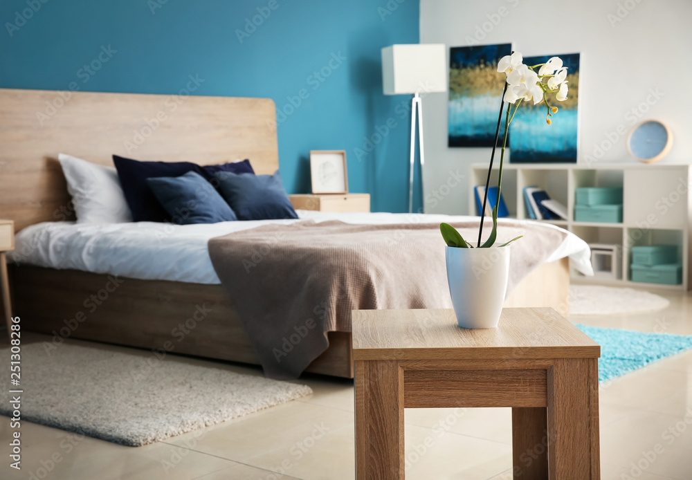 Beautiful orchid in pot on table in bedroom