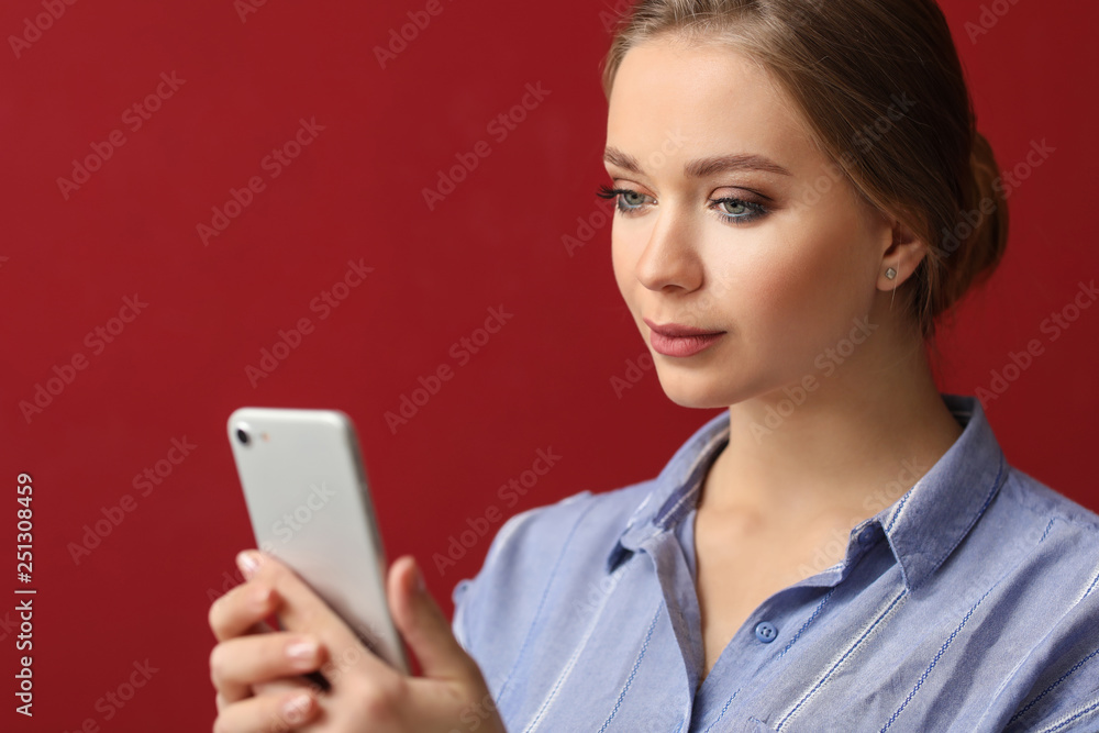 Young woman taking selfie with mobile phone on color background