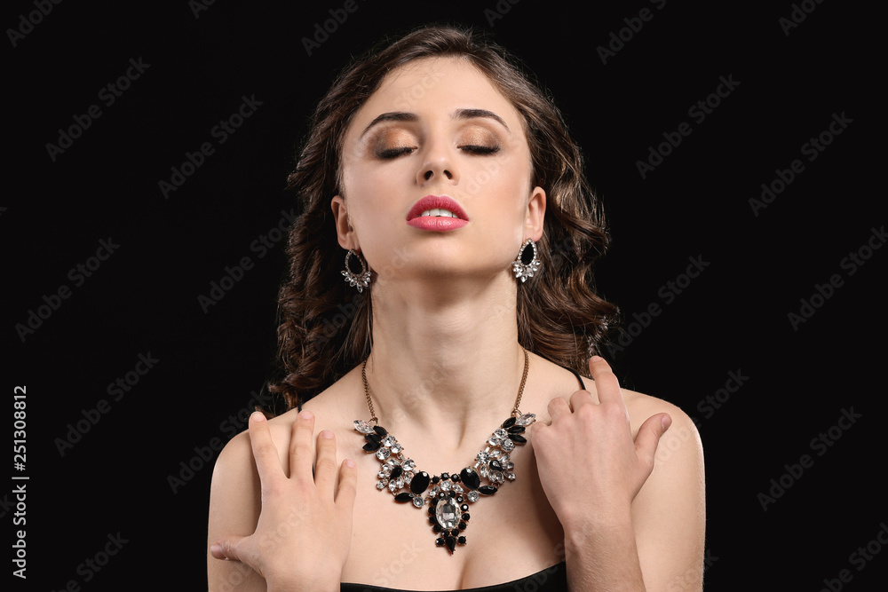 Young woman with beautiful jewelry on dark background