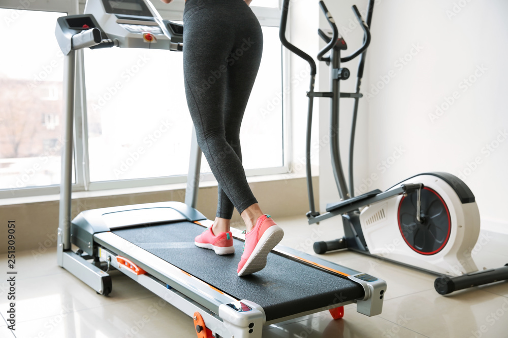 Sporty young woman on treadmill in gym