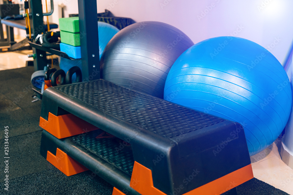 Different kinds of sport equipment in the fitness club indoors. Plastic stands and fitness balls for