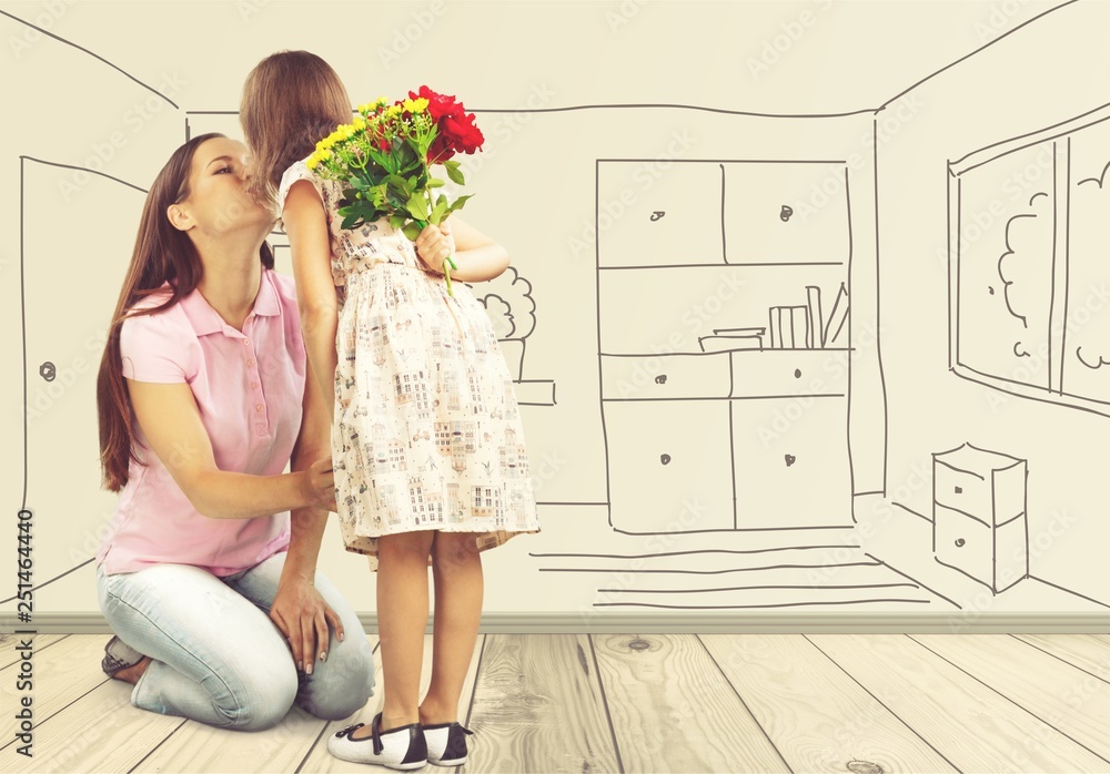 Happy mother and daughter together holding flowers in room