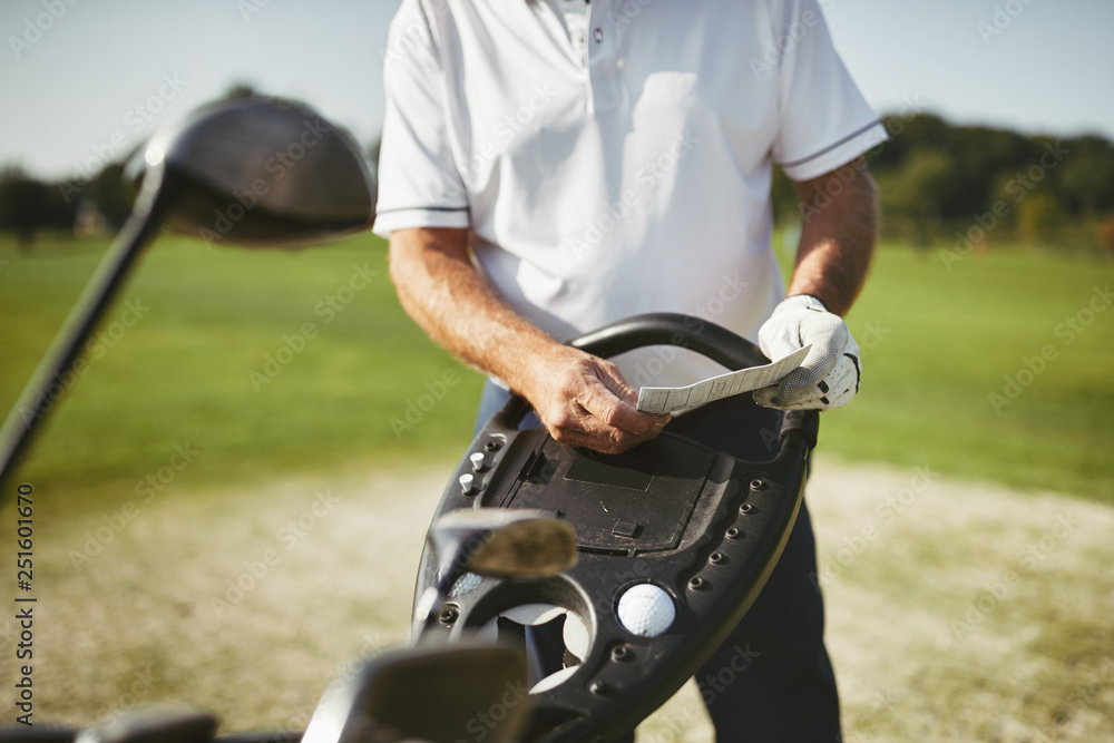 Senior man reading his scorecard during a round of golf