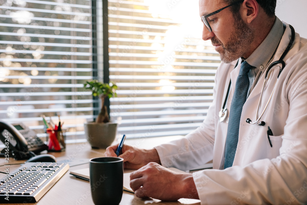 Doctor at office making notes in his diary