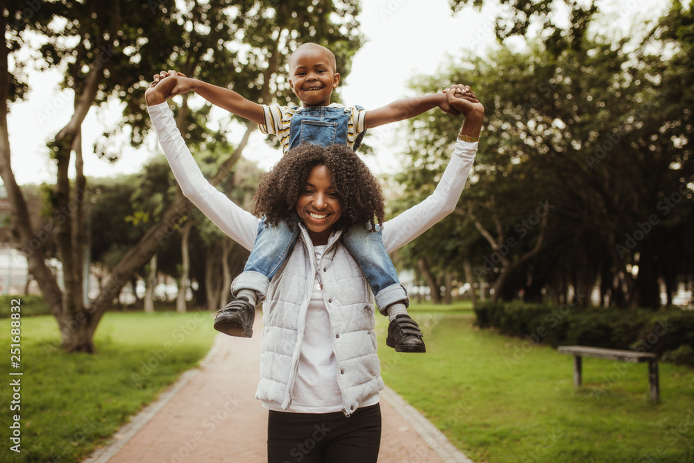 Mother carrying son on shoulders at the park