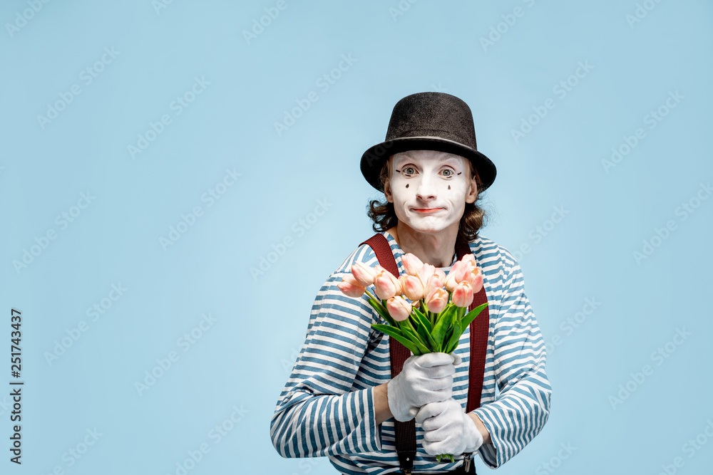 Emotional pantomime posing with tulip bouquet on the blue background indoors. Valentines Day and lo